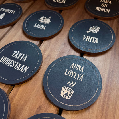 Puinen musta sauna-lasinalunen tekstillä Anna löylyä