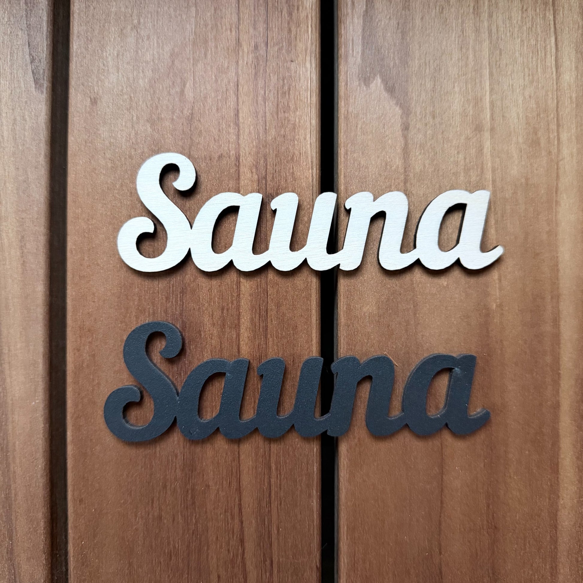 Puinen SAUNA-kyltti saunan oveen luonnonvärisenä ja mustana